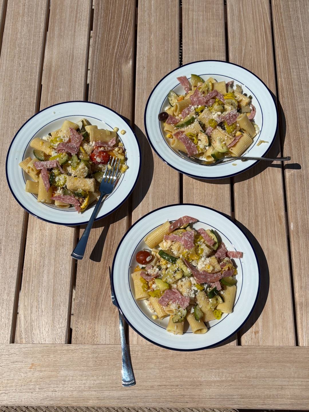 Homemade pasta salad with salami, zucchini, corn, and parmesan plated for dinner